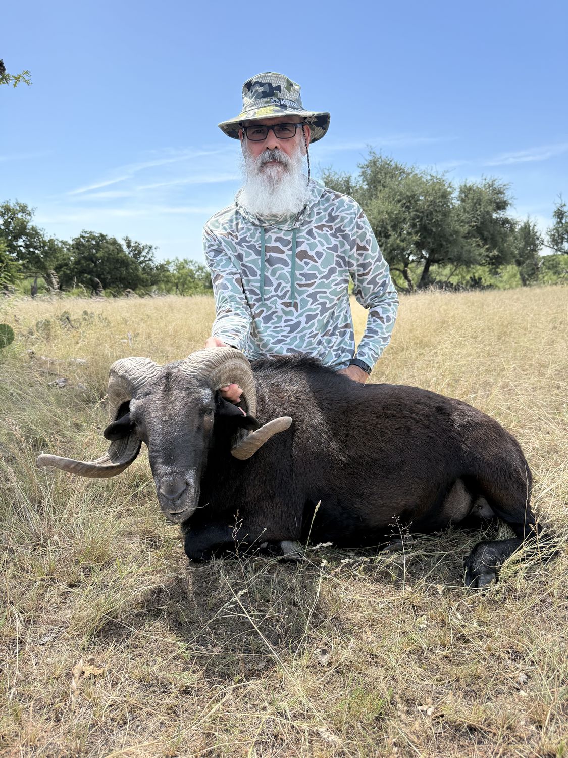 A hunter with a black Hawaiian ram in the Hill Country